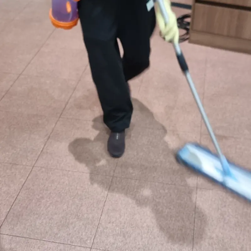 작업자가 예배당 타일 바닥을 밀대걸레로 세척하며 젖은 자국이 남은 모습